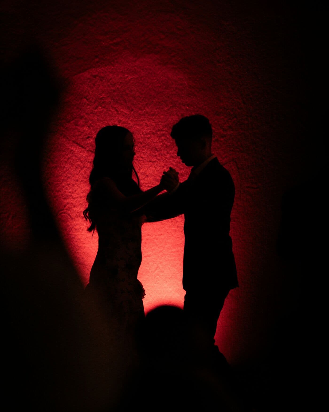 Two people dancing, in silhouette against warm red light