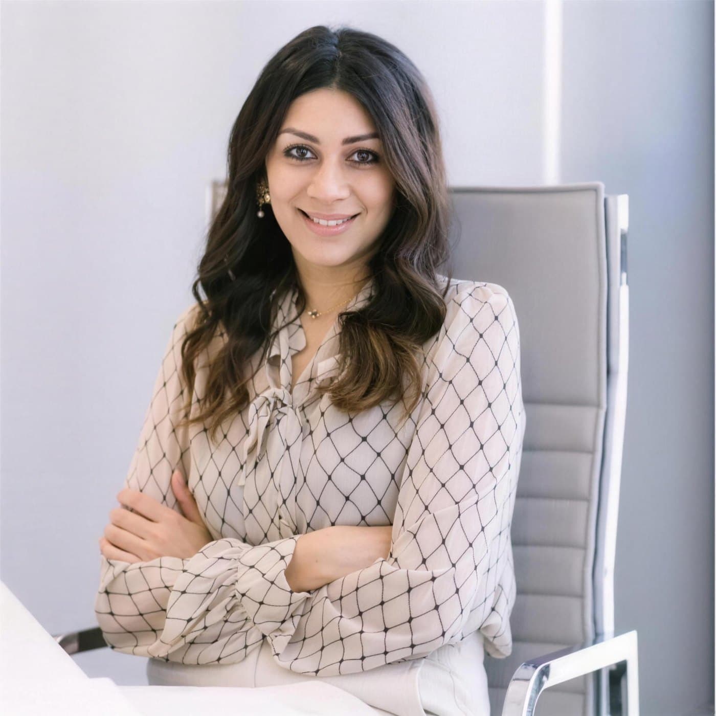 Meghna Shah, smiling, arms folded, in a light patterned blouse